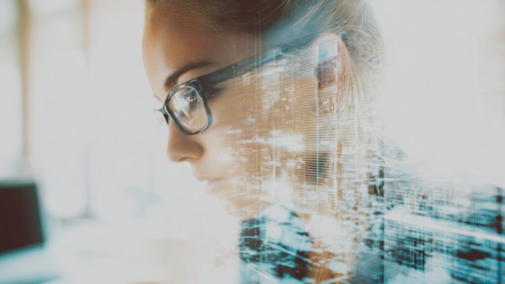 Woman concentrating on laptop with layered digital graphics, representing focus and persistence while building a website